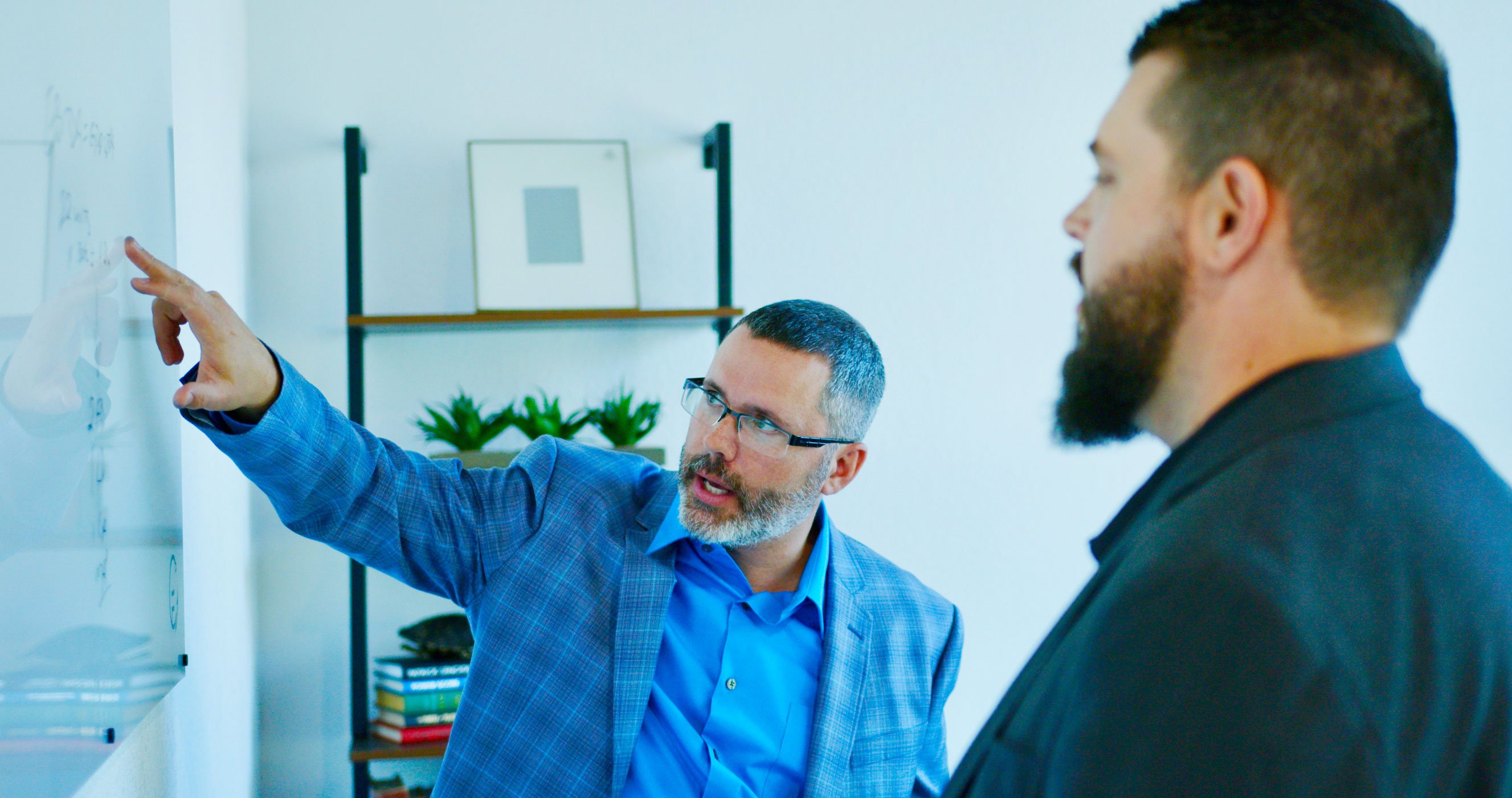 guy pointing at board to another guy